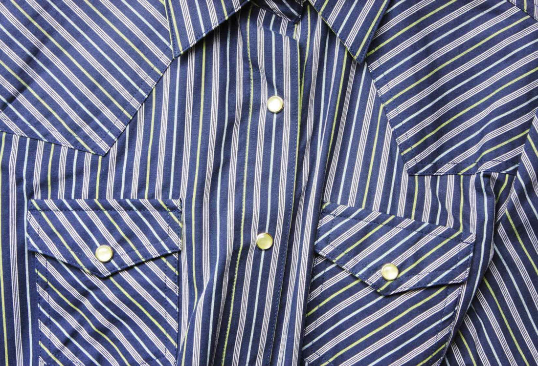 A close up of a western style shirt with pearl snap buttons - Read about the different styles of western shirts on The Western Life at BRAG | Brag Jeans